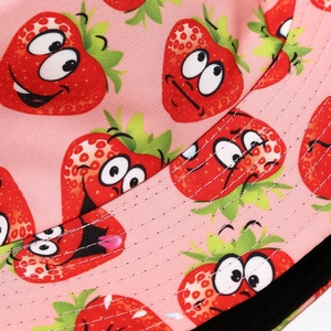 Detailed close-up of pink bucket hat featuring strawberry prints and white stitching line