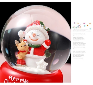 Macro shot of a Christmas snow globe featuring a snowman and deer with Merry Christmas text