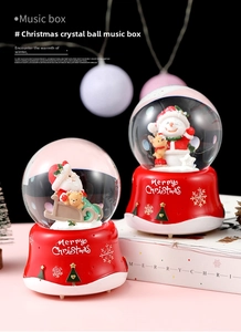 Close-up of a festive red Christmas crystal ball music box with Santa and Merry Christmas text