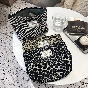 Flat lay of leopard and zebra print canvas makeup bags with Time To Party labels