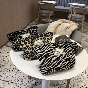 Detailed view of canvas cosmetic bag with animal prints on a white cafe table