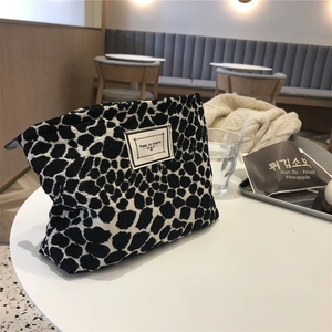 Close-up of canvas makeup bag with black and white spots and 'Time to Party' label on a cafe table