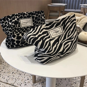 Close-up of leopard and zebra print canvas makeup bags on a table with zipper details