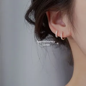 Detail shot of 13mm gold U-shaped huggie earrings with shimmering pavé zircon stones