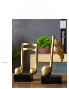 Detailed view of matte gold musical note sculptures on black bases for home decor