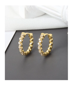 Detailed shot of golden twisted hoop earrings with sparkling cubic zirconia inlay