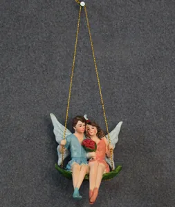 Detail of resin fairy couple miniatures on a green leaf swing with hanging rope
