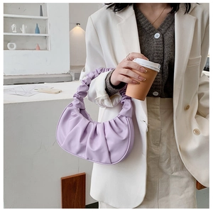 Detail showing the pleated purple crescent handbag texture with refined stitching