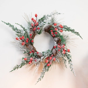 Christmas wreath with red berries, pine cones and snow effect for front door decoration
