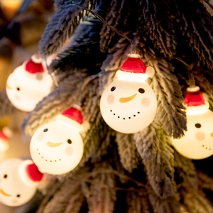 Christmas snowman LED string lights hanging on a snowy tree with warm yellow glow