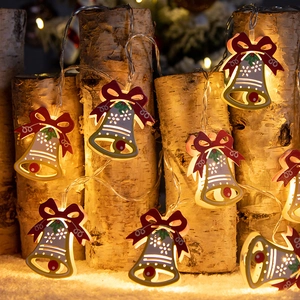 Christmas iron bell LED string lights with red bows on a rustic birch wood stump