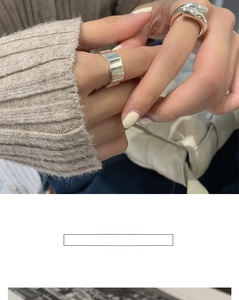 Detail of geometric silver wide band ring and crossover double ring on model hand