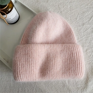 Close-up of thick light pink rabbit fur knit beanie with warm folded cuff and fuzzy texture