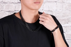 Detail of matte black titanium steel Cuban chain necklace and bracelet on male model