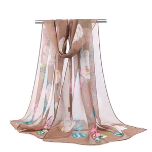 Detail view of brown georgette sun protection scarf with floral lotus pattern on white background