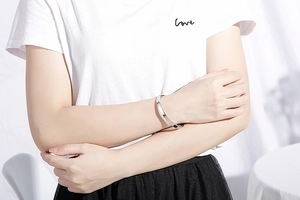 Gros plan d'un bracelet jonc minimaliste en acier inoxydable poli porté sur un mannequin