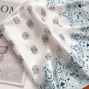 Detailed macro view of vintage paisley silk scarf with elegant blue patterns on white fabric