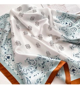 Detail of silk-like paisley square scarf with vibrant burnt orange borders and smooth texture
