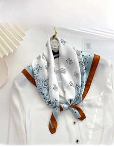 Detail of vintage paisley silk scarf tied on a white shirt collar for elegant styling