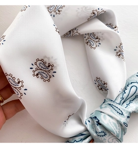 Macro shot of paisley print silk scarf showing white and light blue satin fabric texture