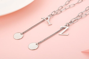 Close-up of silver Y and Z initial pendants with unique paperclip and box chain