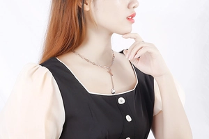 Detail of rose gold Y-letter pendant necklace with round charm worn on model neckline