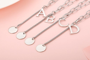 Detail view of initial letters A to D on silver chain necklaces with mixed link textures