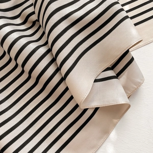 Close-up of black and white striped silk scarf showing glossy texture and fabric folds