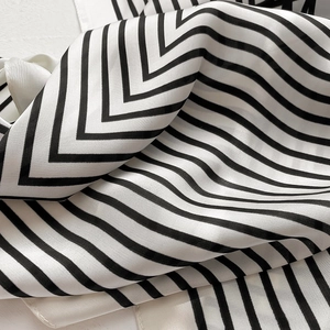 Close-up of black and white striped silk scarf showing smooth texture and soft folds