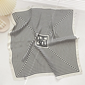Detail of a square silk scarf with black and white stripes and center logo pattern