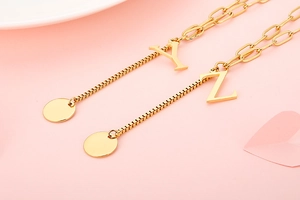 Close-up of gold stainless steel necklace with Y and Z letter pendants and paperclip chain