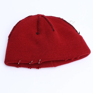 Detail of dark red knit beanie with silver rings, distressed edges and black stitching
