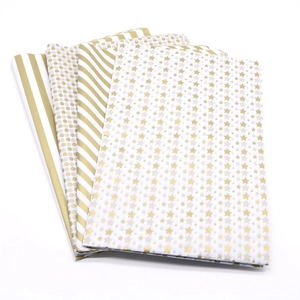 Detail of gold foil tissue paper with star, dot and stripe patterns for gift wrapping