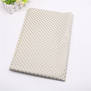 Detail of white gift wrap paper featuring metallic gold dots and grey square patterns