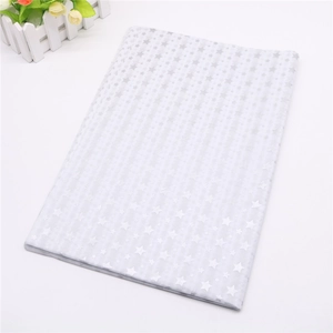 Detail of white gift wrapping tissue paper with gold star and stripe patterns