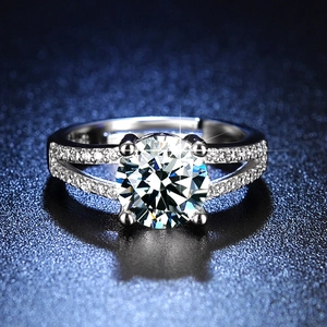 Close-up of a silver six-prong moissanite ring with split shank on a blue background