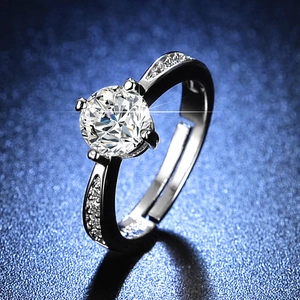Macro detail of silver six-prong moissanite ring with side stones on dark blue background