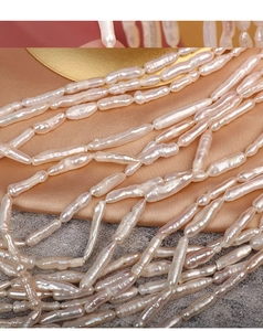 Macro shot of lustrous baroque toothpick pearls strands on champagne silk fabric background