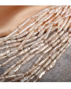 Macro detail of natural Baroque stick pearls with high luster on champagne silk fabric
