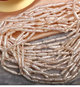 Macro shot of lustrous white baroque stick pearls with natural texture on silk fabric