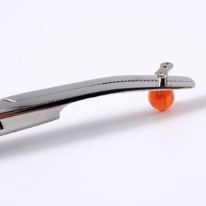 Macro view of stainless steel piercing forceps holding a small orange dermal anchor