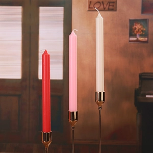 Close-up of red, pink, and ivory taper candles set in elegant gold holders for home decor