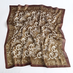 Detailed close-up of brown paisley pattern on smooth satin silk square scarf