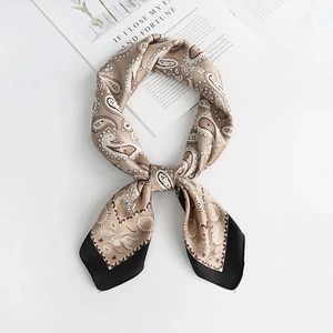 Detail of silk-like scarf with paisley pattern, golden accents, and black borders