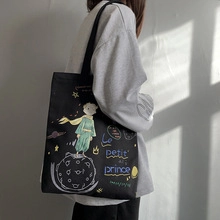Vue latérale du sac cabas en toile noire avec illustration du Petit Prince porté par un modèle