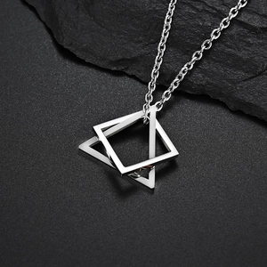 Silver geometric triangle and square pendant necklace on a textured black rock background