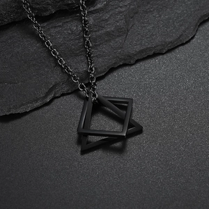 Minimalist black geometric triangular pendant necklace on a natural stone surface
