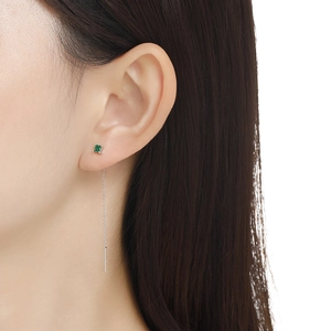 Detail of s925 silver threader earring with a small green square gem on female ear