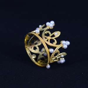 Detailed view of a golden crown with pearl accents on a black background