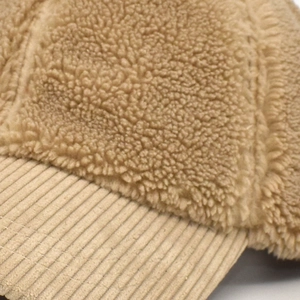 Detailed view of the brown sherpa fleece crown and textured corduroy brim on this winter cap